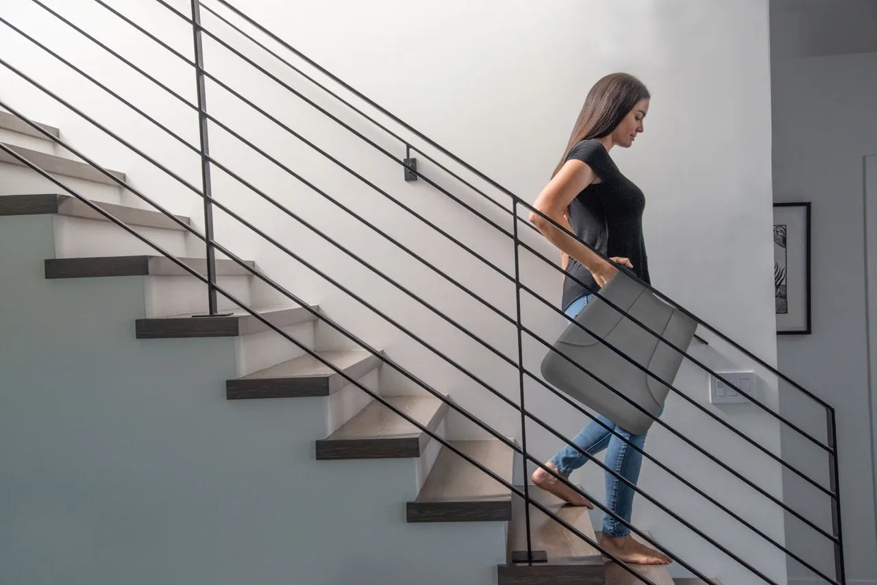 A woman carrying the folded Ready Rocker down the stairs