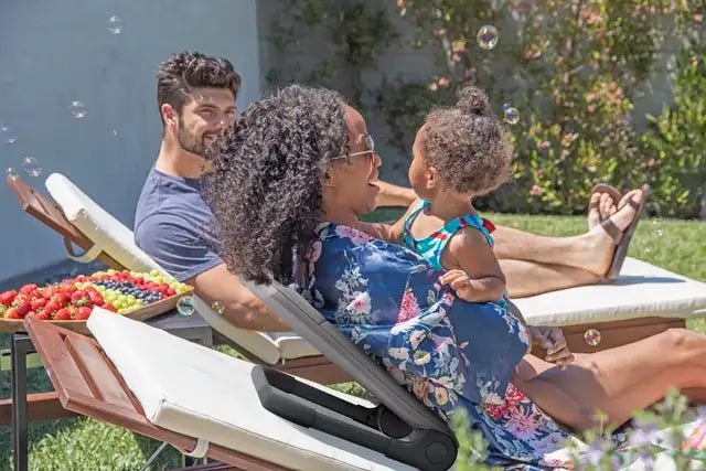 A family relaxing on garden loungers, the mother leaning back on a Ready Rocker