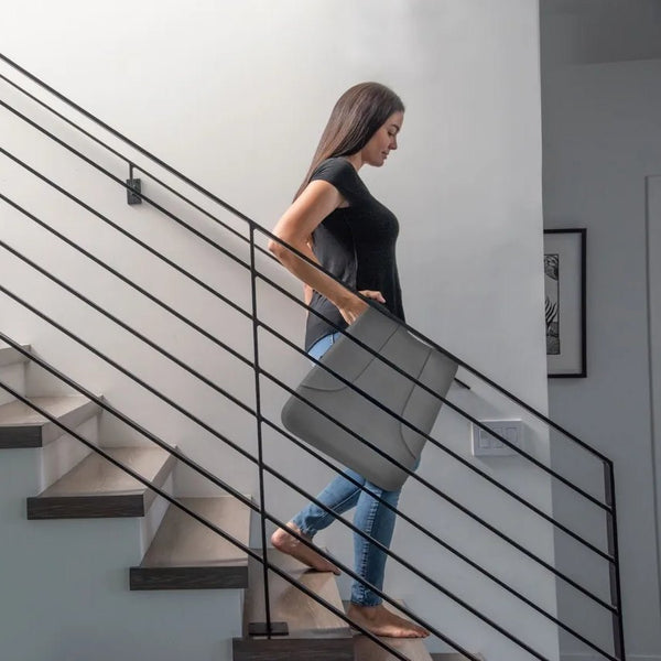 A woman carrying the folded Ready Rocker up the stairs by its handle