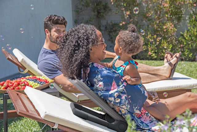 A family relaxing outdoors on lounge chairs with the Ready Rocker