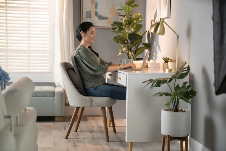 A woman working at her desk, sitting on the Ready Rocker in a dining chair
