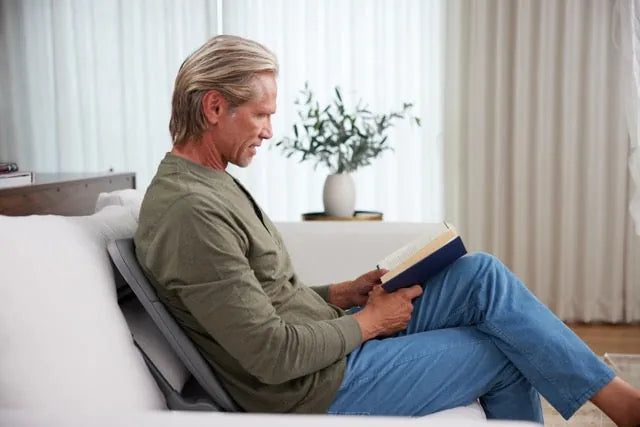 Man reading on a sofa with the Ready Rocker behind his back